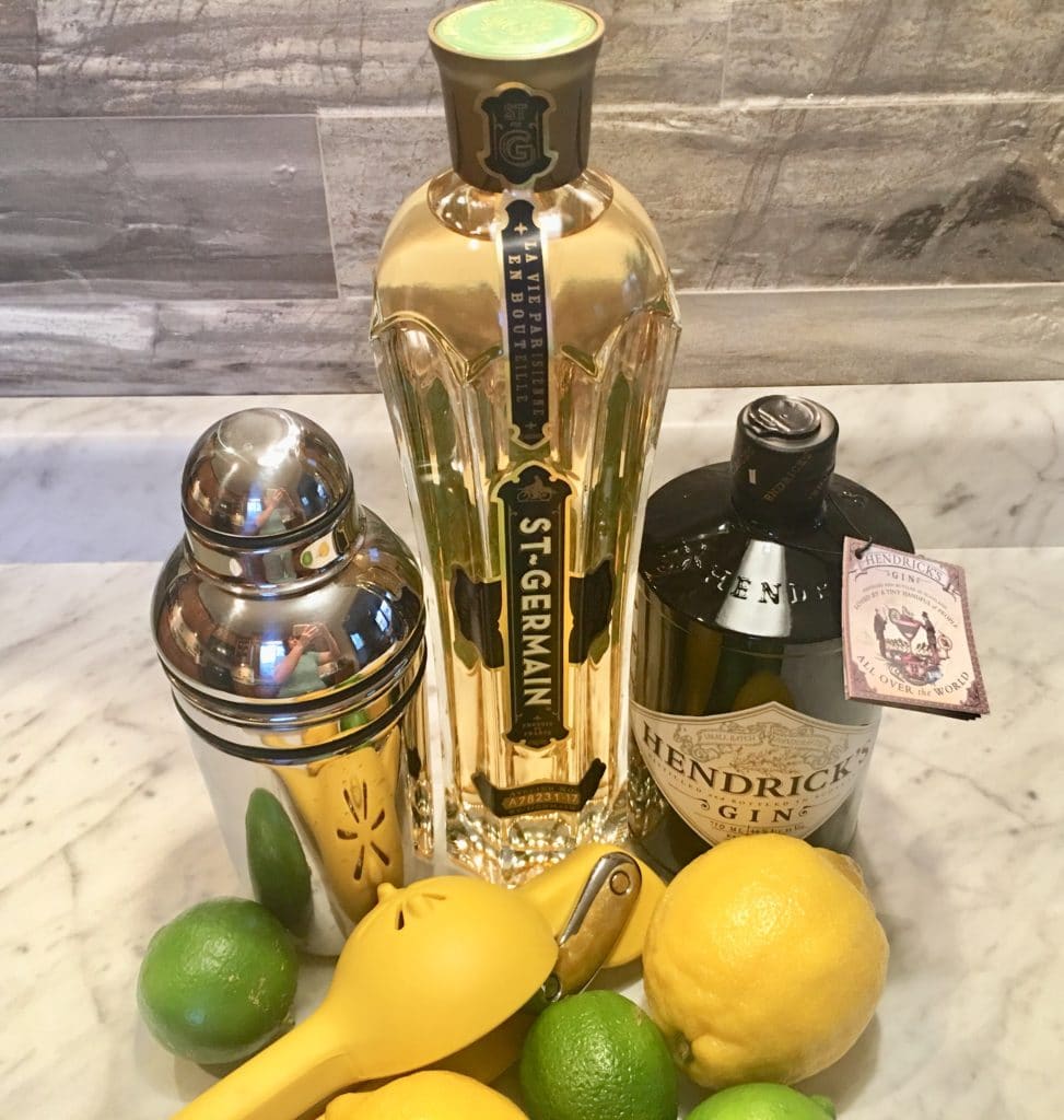 Hendrix Gin, St. Germina, lemons, limes, and shaker on a counter.