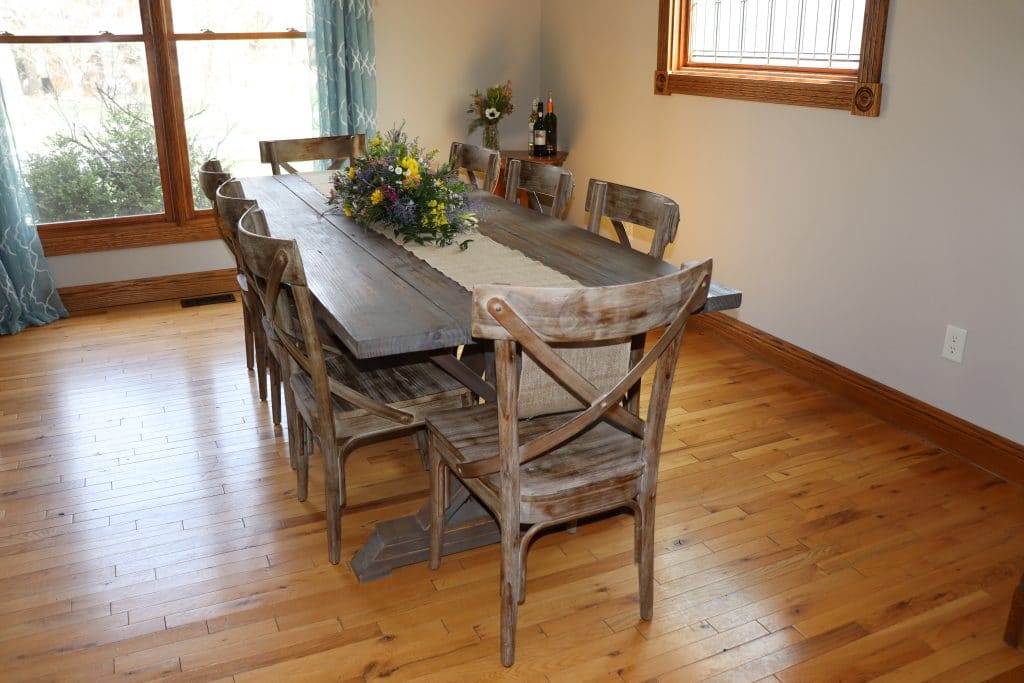 Dining room with a homemade table that has a burlap runner and a flower arrangement in the center.