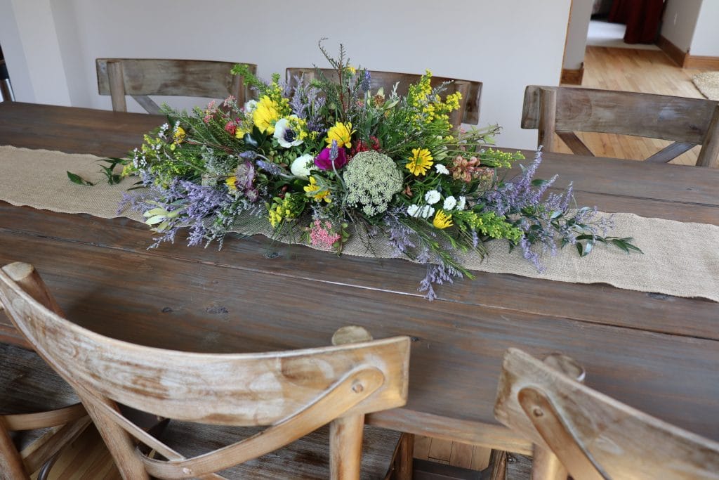 Photo of rustic flowers centerpiece on burlap runner.