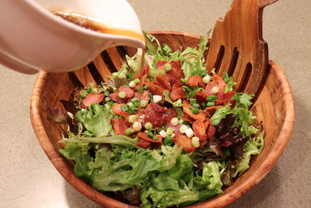 Pouring hot dressing on salad