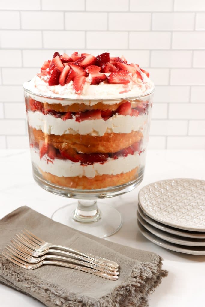 trifle bowl with layered dessert and plates and napkins on the counter