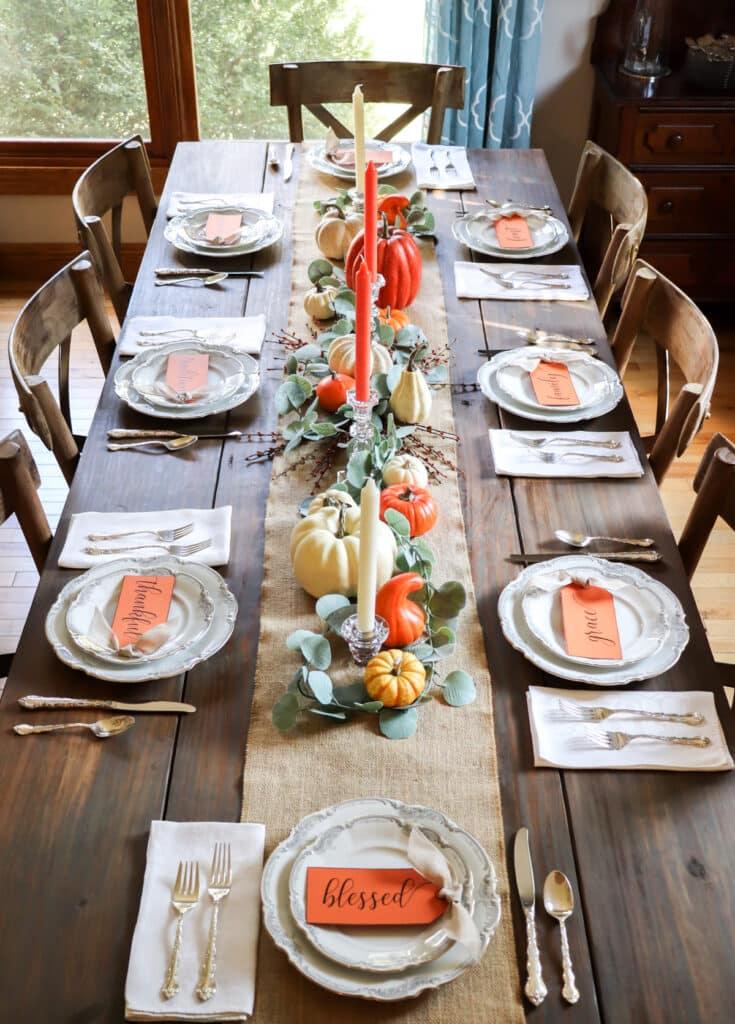 pumpkin tablescape with lots of pumpkins, candles, china, silverware, and printable tags