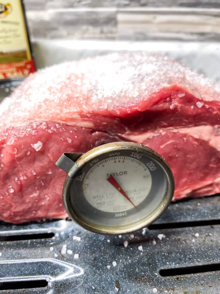 meat thermometer in middle of a cur of prime rib roast with salt on top
