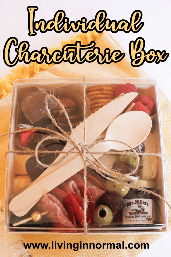 individual charcuterie box pinterest image of box with meats, fruits, cheeses, olives, crackers and silverware tied together with twine.