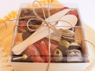 Charcuterie Box filled with meats, cheese, olives, nuts and fruit with brown twine tied around it.
