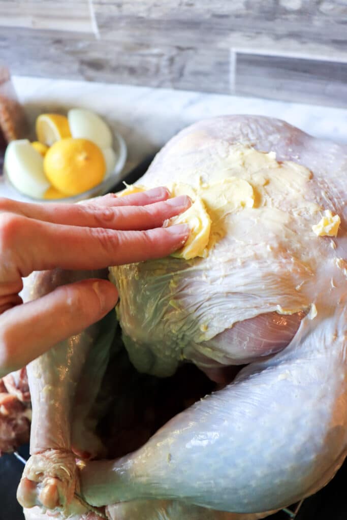 Rubbing softened butter on top of the turkey skin.
