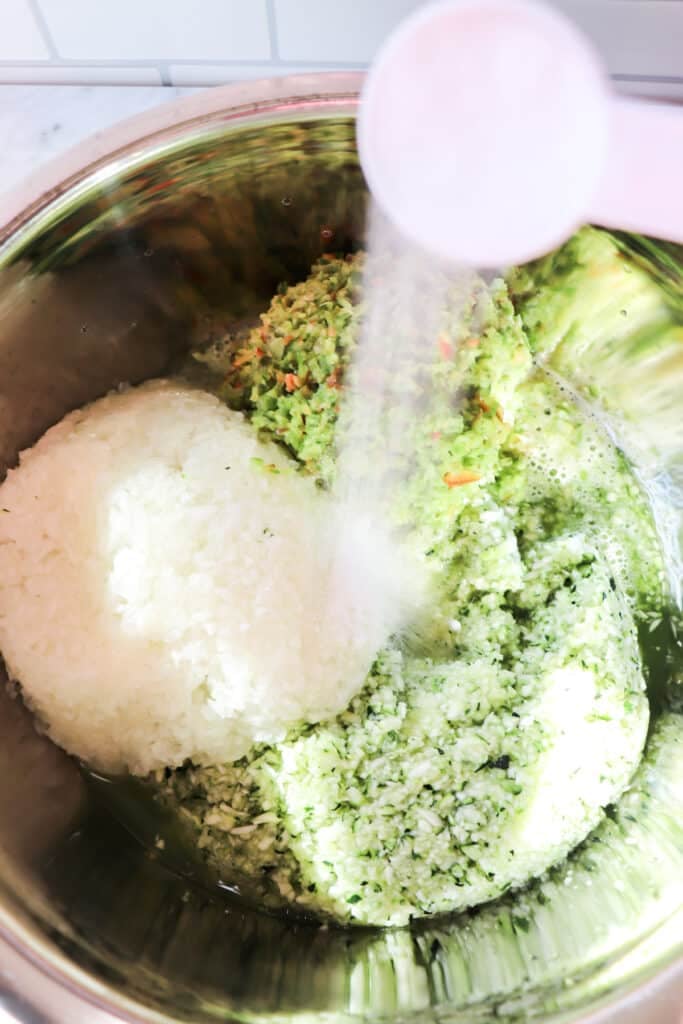 Pouring salt on top of the chopped vegetables in a bowl.