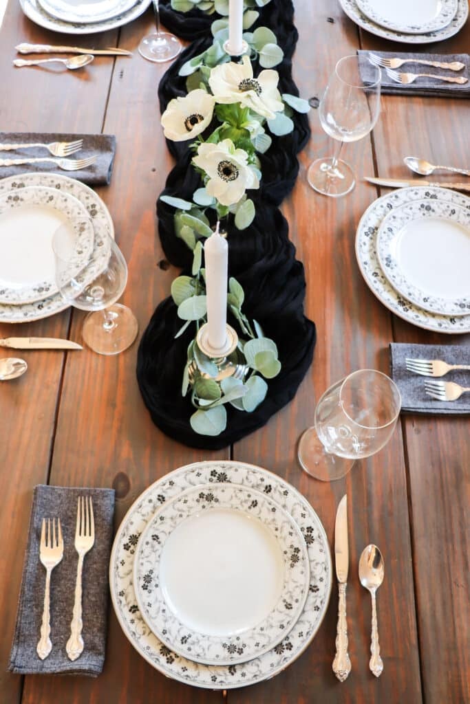 Overhead view of several place settings with black and white flowers in the middle.