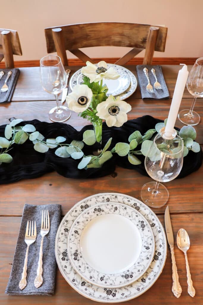 One place setting with the black and white flowers and candles sitting in the background.