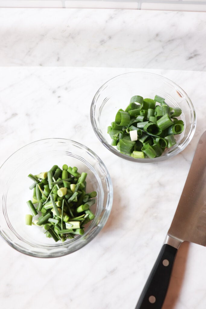 Garlic scapes and green onions chopped in bowls.