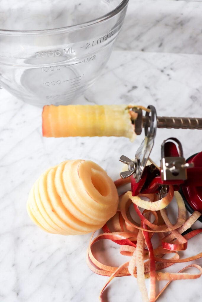 Apple peeler, corer, slicer on the counter with a sliced apple.